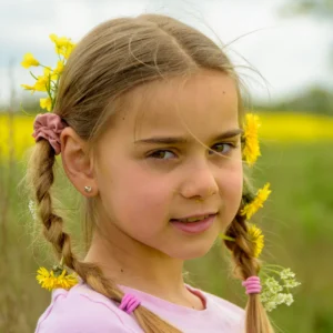 Headshot of young girl in an outdoor setting with yellow flowers in her hair