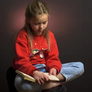 A young girl reading a book in a studio setting captured by Dick Lloyd Photography