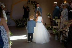 Flower girl and page boy walking down the aisle in soft sunlight.