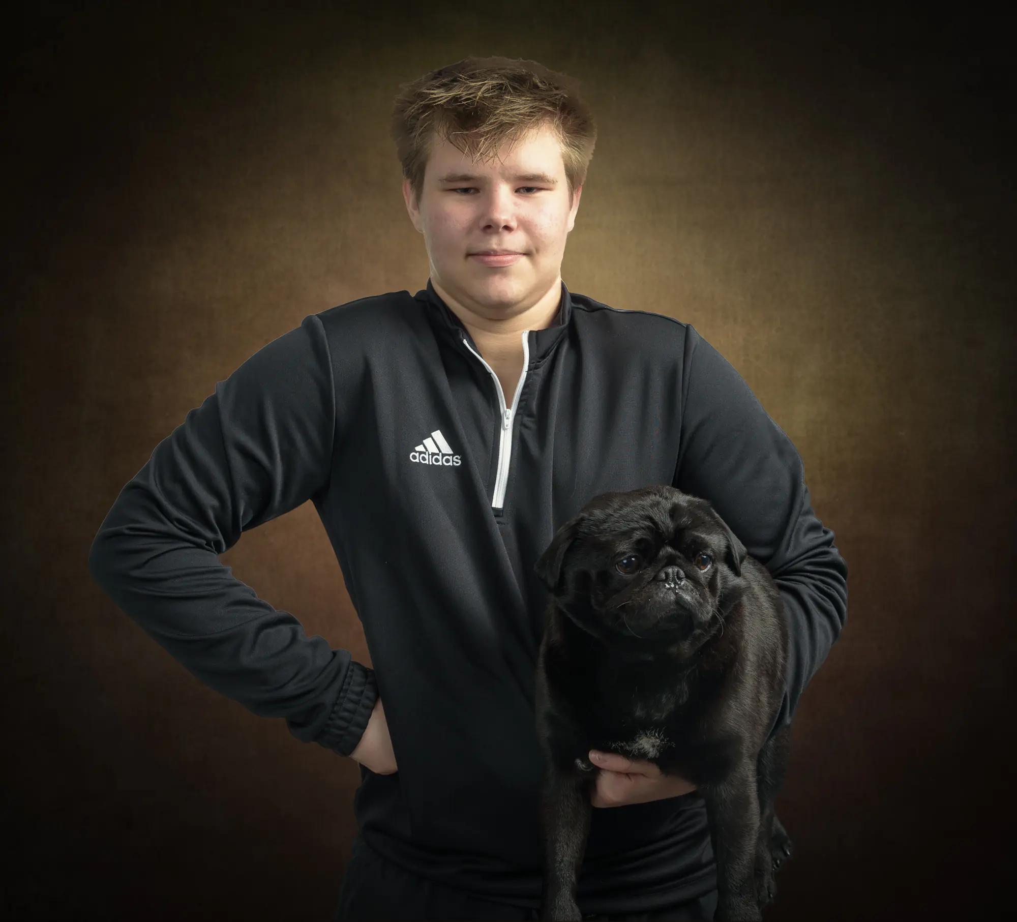 Portrait of a teenage boy with his pet dog, soft light with a brown textured background - by Dick Lloyd Photography