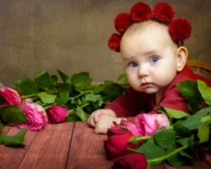 Baby surrounded by red roses - soft light with a brown textured backgrounbd - by Dick Lloyd Photography