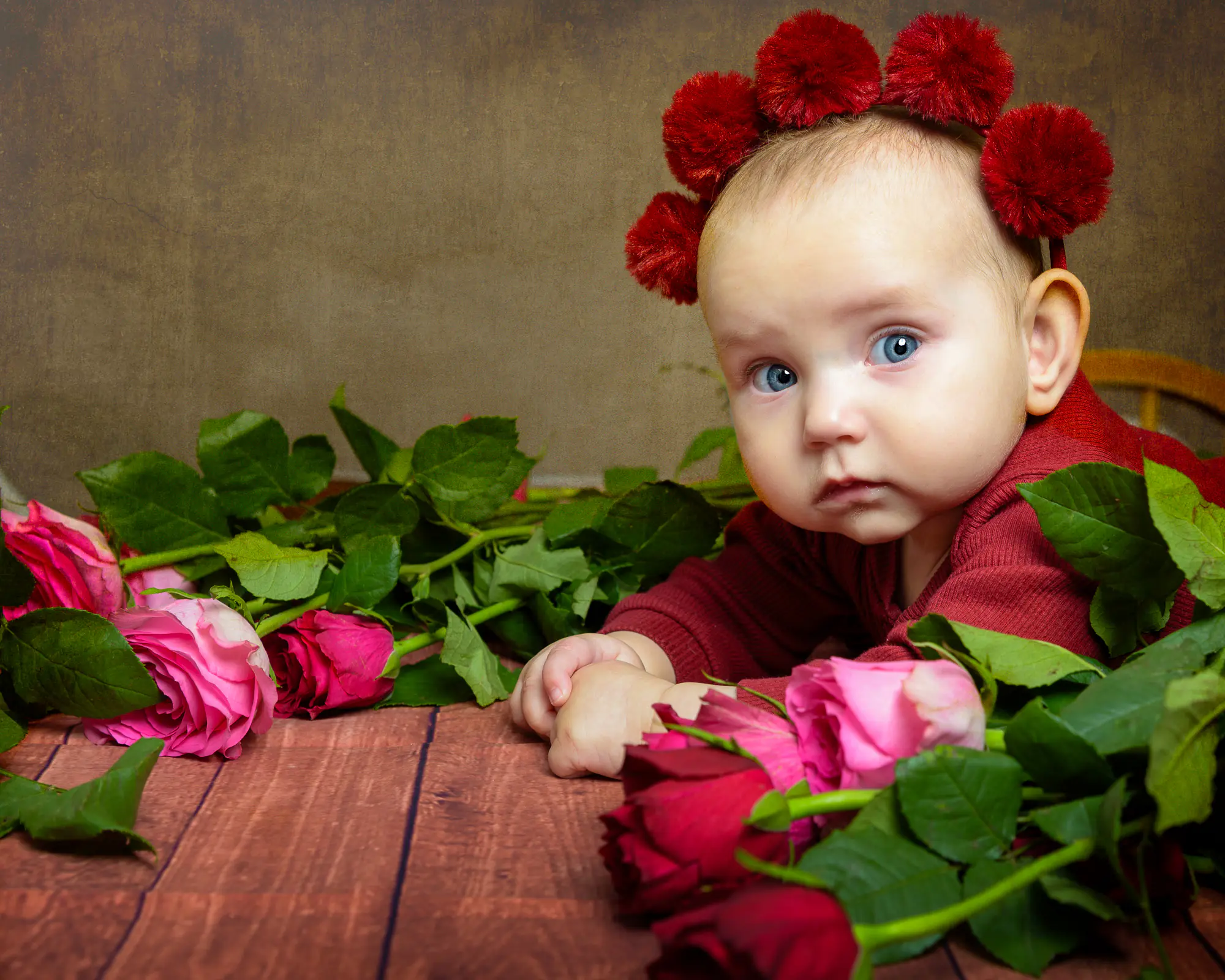 Baby surrounded by red roses - soft light with a brown textured backgrounbd - by Dick Lloyd Photography