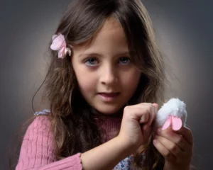 Studio portrait of a young girl with her cuddly soft toy - soft light with a grey background.