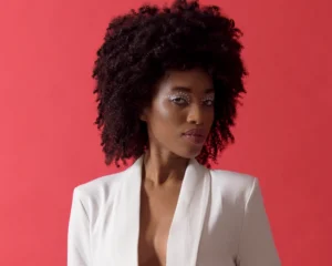 Half-body shot of model wearing a white jacket with contrasting red background by Dick Lloyd Photography