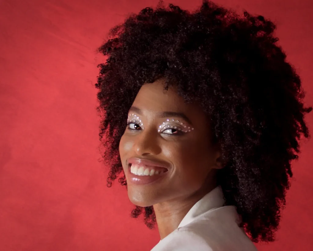 Headshots for acting – confident actress smiling against red studio backdrop, photographed in Harrogate by Dick Lloyd