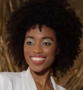 Actress headshot: smiling Black female model in studio before a golden backdrop — portfolio shot by Dick Lloyd Harrogate
