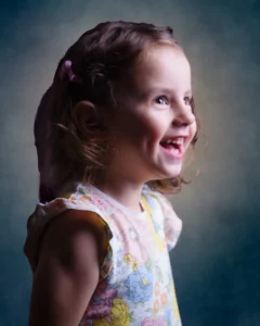 Joyful toddler girl laughing during a portrait session, captured in soft studio lighting for a children’s photography collection.