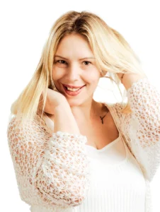 High-key studio portrait of a smiling woman touching her hair.