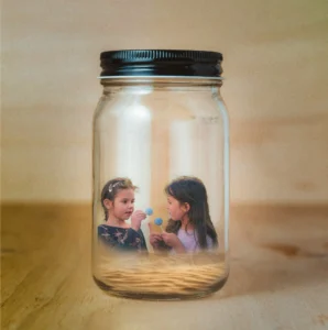 Whimsical composite of two young girls inside a glass jar holding lollipops — creative children’s portrait.