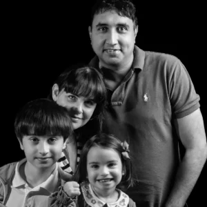 Black and white studio portrait of a family of four smiling together.