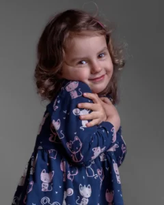 Studio portrait of a shy young girl with soft lighting against a grey background.