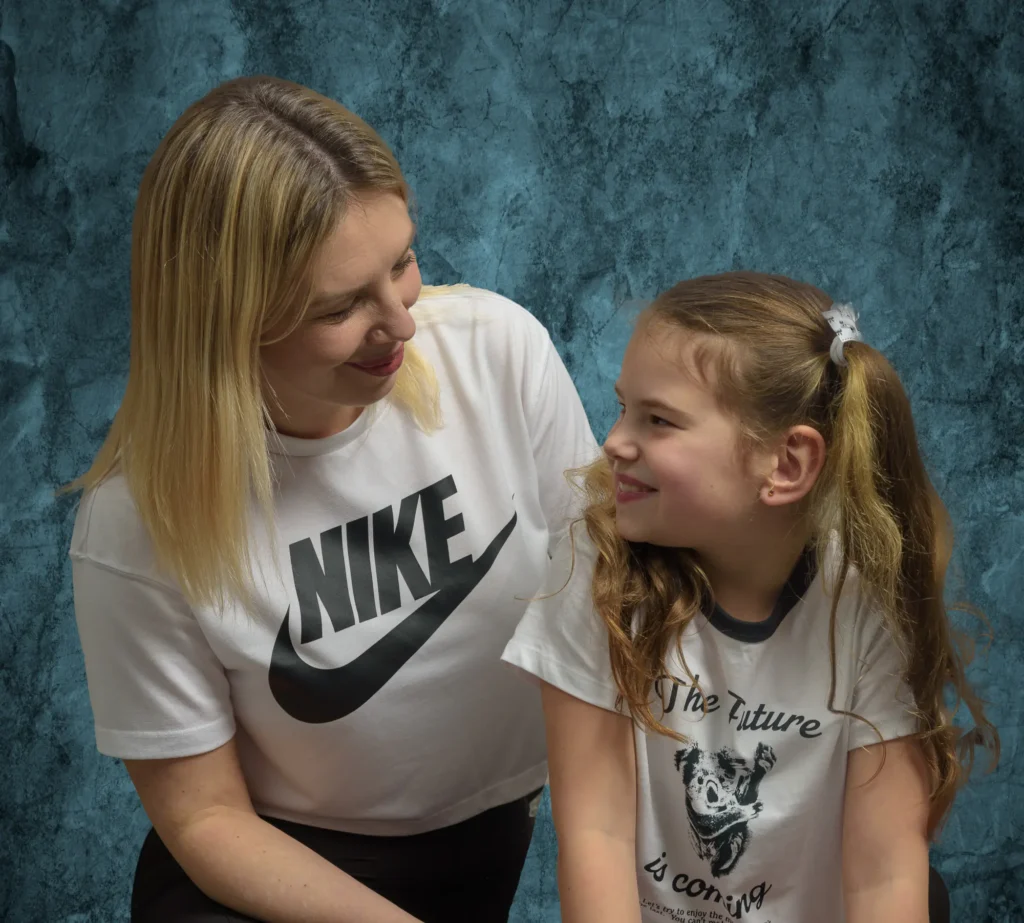 Indoor studio portrait of a mother and daughter with a subtle textured blue background adding depth without distraction