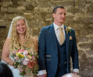 Bride and groom standing during the ceremony, holding hands and smiling.