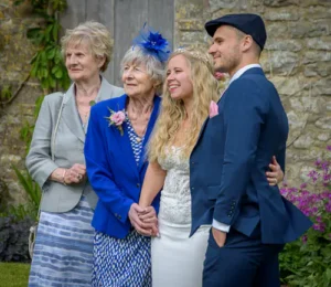 Bride's’s family group photo outdoors against a stone wall.
