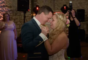 Bride and groom laughing with a large group of guests in the background.