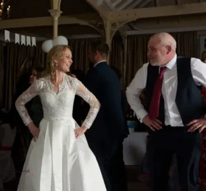Bride and groom dancing together with hands on hips, laughing.